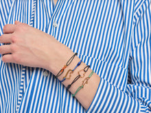 画像をギャラリービューアに読み込む, 複数の種類の金のコードブレスレットをつけた女性の手