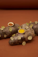 画像をギャラリービューアに読み込む, 複数の天然石のついた18金の指輪がおかれている