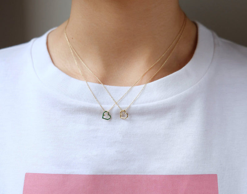 複数のダイヤモンドのついたハートの金のネックレスをつけた女性