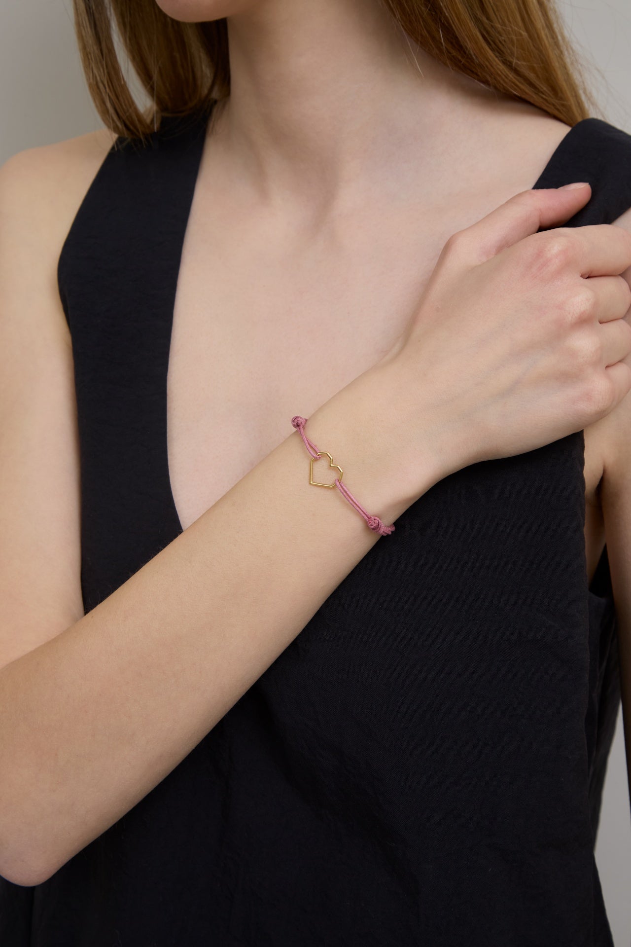 複数の種類の金のコードブレスレットをつけた女性の手