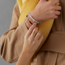 画像をギャラリービューアに読み込む, 複数の種類の金のアクセサリーをつけた女性の手
