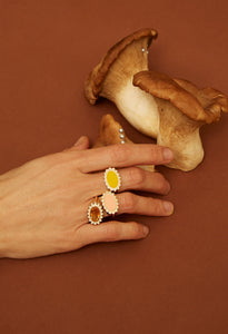 複数の天然石のついた18金のリングをつけた女性の手