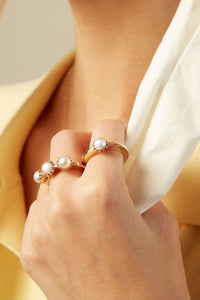複数のパールのついた18金の指輪をつけた女性の手
